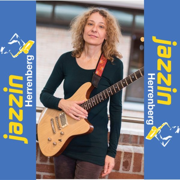 Barbara Jungfer mit Gitarre und Jazzin-Bannern